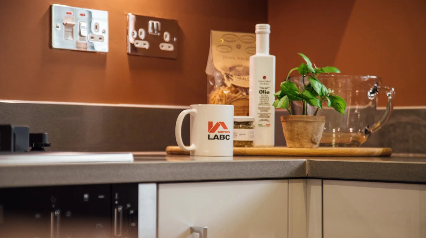 Lifestyle image of LABC Warranty mug and olive oil in kitchen